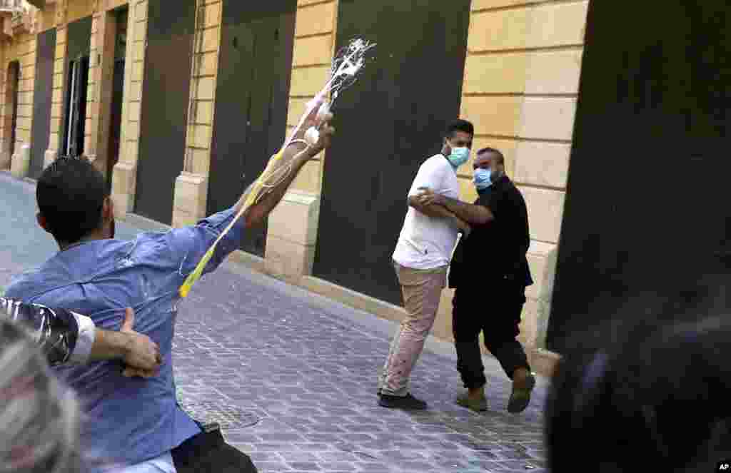 A bank customer throws eggs toward the guards of a bank, during a protest in Beirut, demanding that they be allowed to withdraw their deposits that have been blocked amid Lebanon's severe financial and economic crisis. 