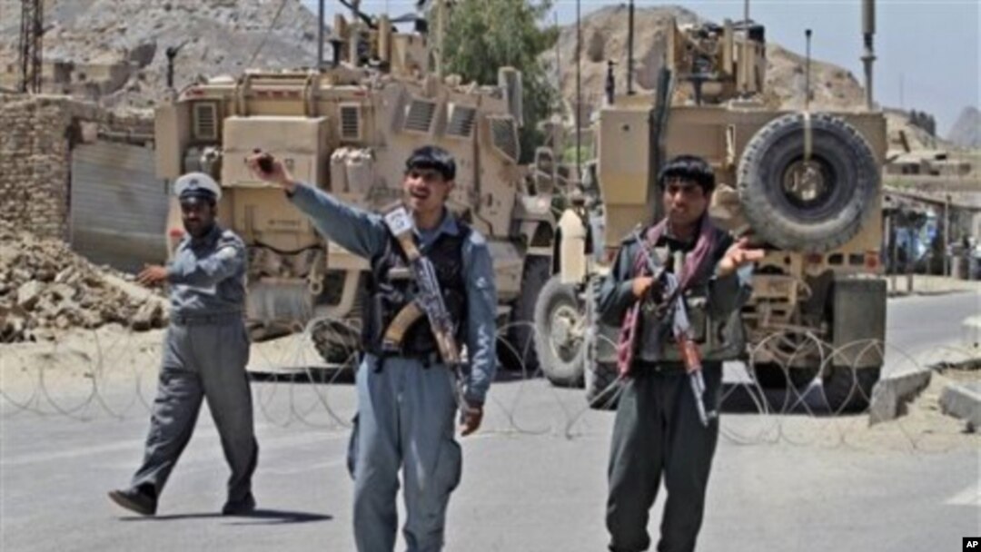 Afghan policemen and armored NATO military vehicles stand guard close to the main prison in Kandahar, south of Kabul, Afghanistan, April 25, 2011