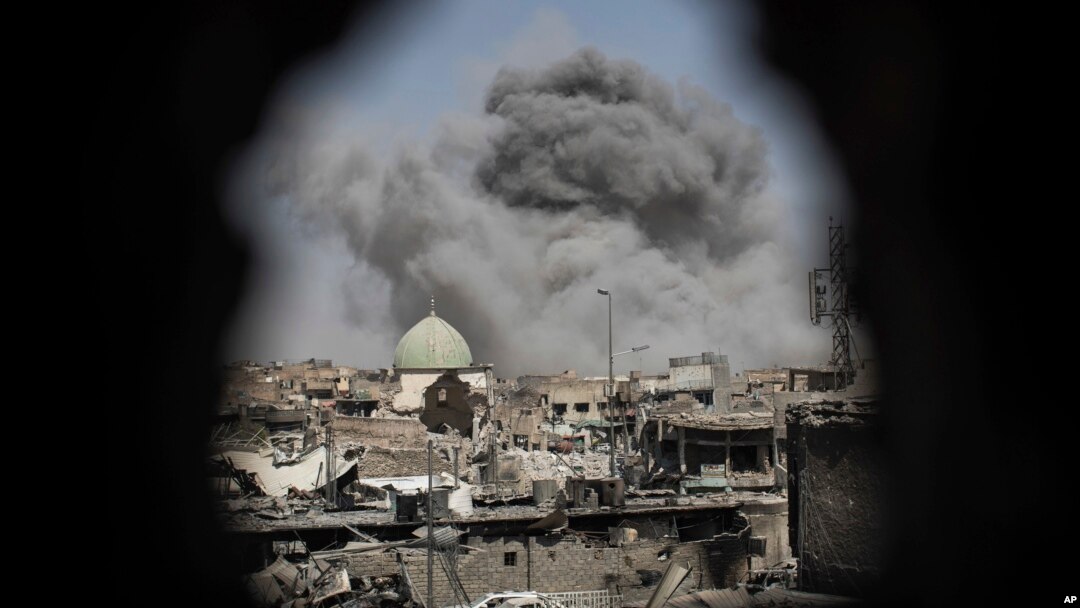 Una bomba explota detrás de la mezquita de al-Nuri en una foto captada a travez del orificio en una casa en Mosul.