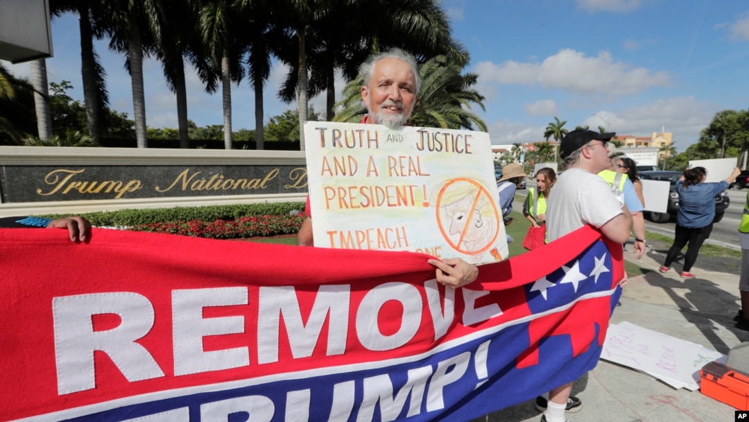 Ray Bonachea holds a sign in favor of the impeachment of President Donald Trump, outside of the Trump National Doral Miami golf resort, Dec. 17, 2019, in Doral, Fla. 