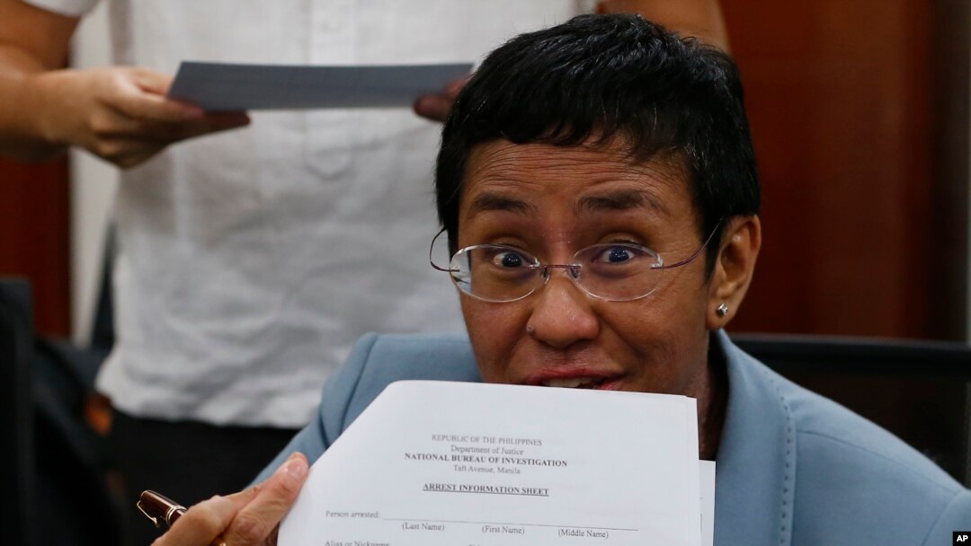 Maria Ressa, the award-winning head of a Philippine online news site Rappler that has aggressively covered President Rodrigo Duterte's policies, shows an arrest form after being arrested by National Bureau of Investigation agents in a libel case, Feb. 13, 2019.