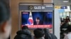 La gente mira una transmisión televisiva en vivo del presidente de Corea del Sur, Yoon Suk Yeol, haciendo una reverencia después del final de su discurso a la nación, en una estación de tren en Seúl, el 7 de diciembre de 2024.