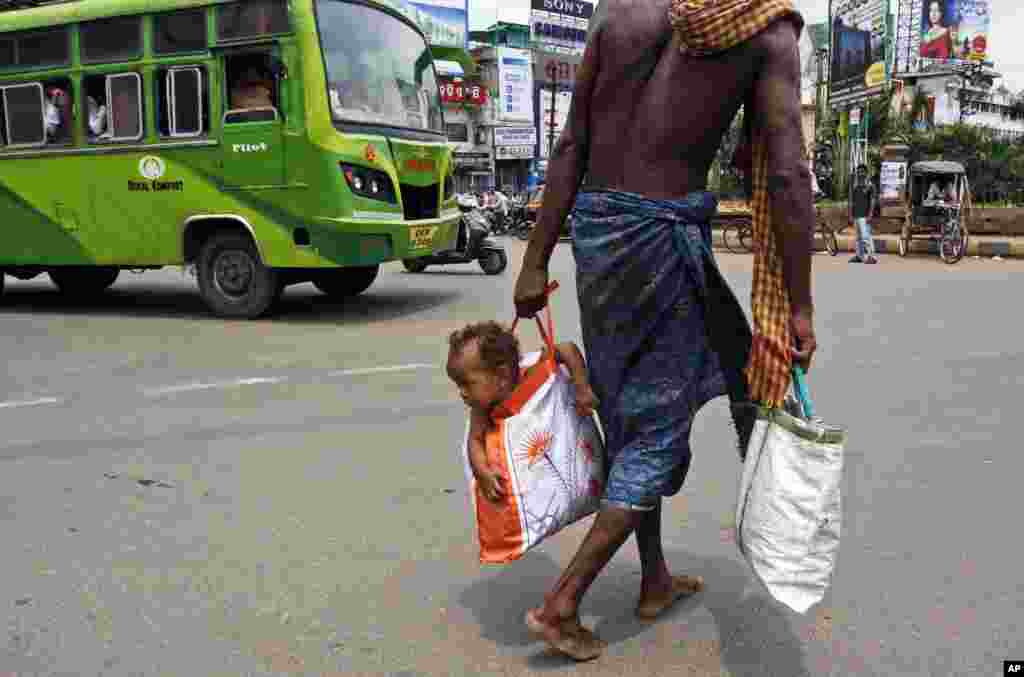 A man carries his child in a bag as he crosses a street in Bhubaneswar, India.