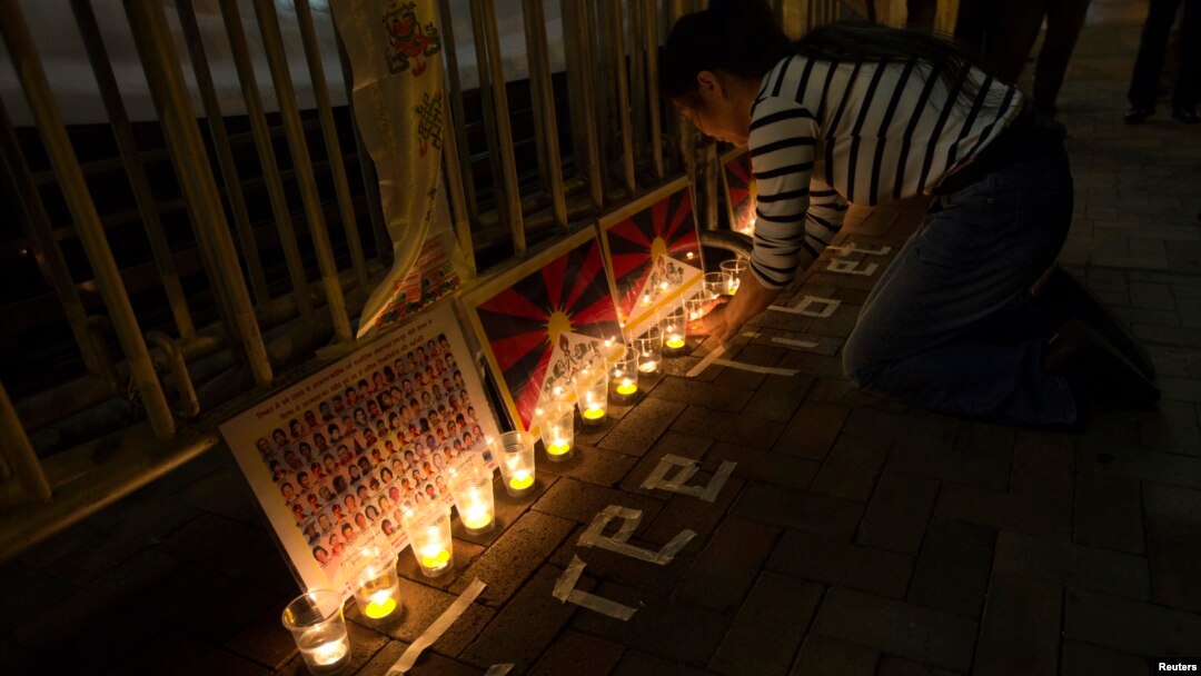 A protester arranges candles during a candlelight vigil outside a China Liaison Office in Hong Kong, February 13, 2013.