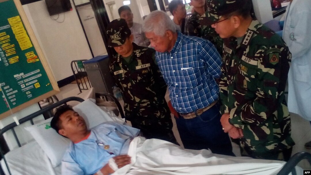 Philippines Defense Secretary Voltaire Gazmin (2nd R) and military chief General Hernando Iriberri (R) visit one of the 53 wounded soldiers at a military hospital in Zamboanga on the southern Philippine island of Mindanao on April 10, 2016, a day after soldiers clashed with the extremist Abu Sayyaf group. 