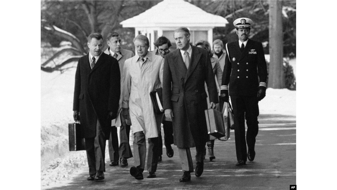 FILE - President Jimmy Carter, flanked by Secretary of State Cyrus (right) and his adviser on foreign policy, Zbigniew Brzezinski (left), walk toward a waiting helicopter to fly to the nearby Andrews Air Force Base, Md.