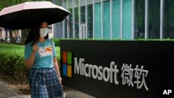 資料照片：一位女士走過微軟公司在北京的辦公樓。 (2021年7月20日)