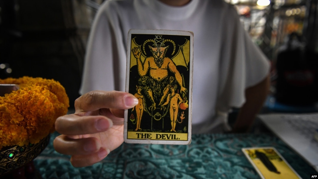 FILE - A fortune teller poses with tarot cards at a temple in Bangkok, Feb. 12, 2019.