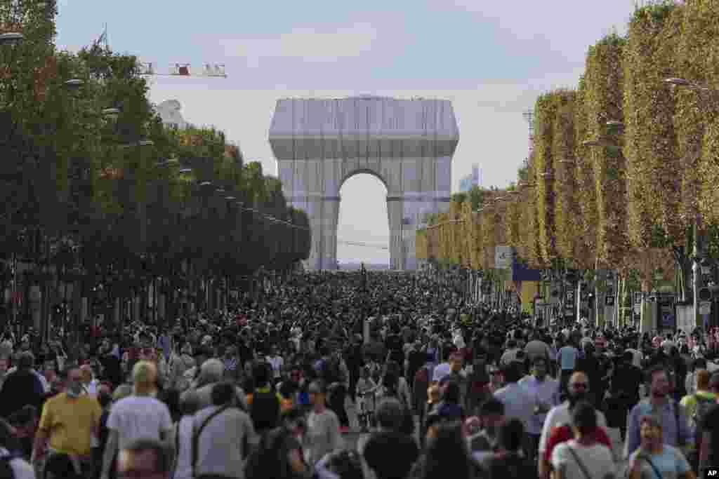 People walk along the Champs Elysees Avenue, Paris, during the "day without cars", with the Arc de Triomphe in the background.