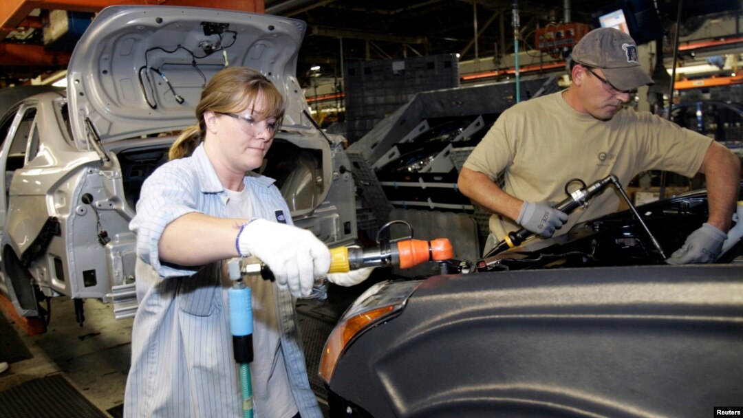 FILE - A female employee works alongside a male colleague at a Ford Motor Plant in Wayne, Michigan.
