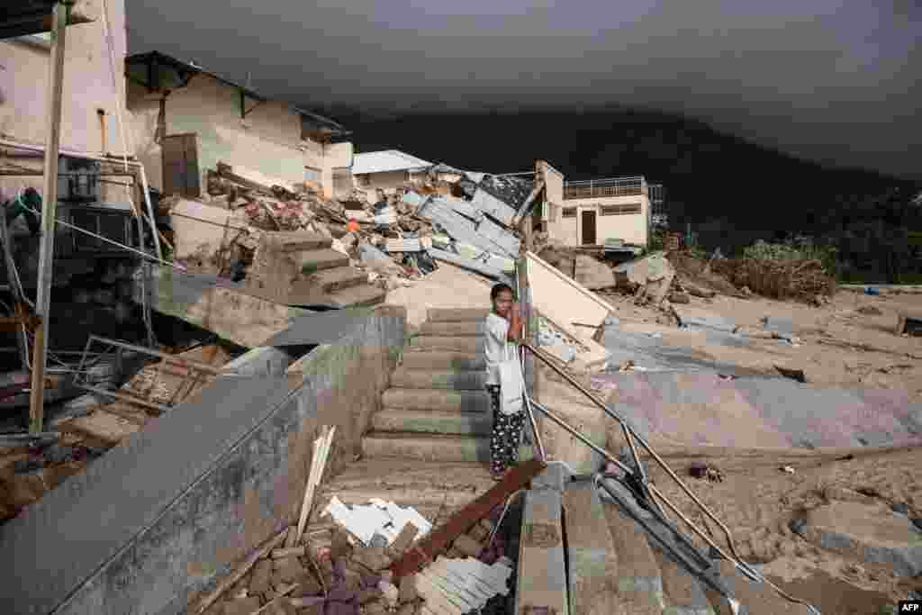 A woman stands before a collapsed building of a school next to a beach in the aftermath of Typhoon Mangkhut in the coastal village of Shek O in Hong Kong.