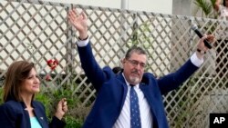 Bernardo Arévalo, candidato presidencial por el partido Movimiento Semilla, y la compañera de fórmula Karin Herrera saludan a sus seguidores fuera del edificio de la oficina del Fiscal General de Guatemala en la Ciudad de Guatemala, el 13 de julio de 2023.