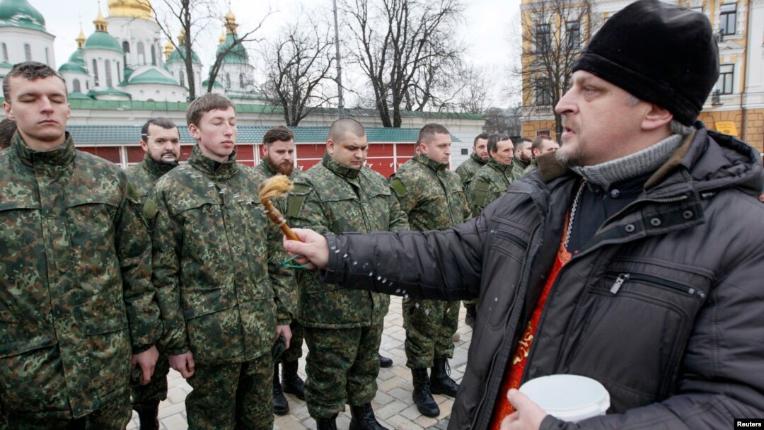 An Orthodox priest blesses members of the newly created Ukrainian interior ministry battalion "Saint Maria" during a ceremony before they head to militay training, in front of St. Sophia Cathedral, in Kyiv, Feb. 3, 2015. 