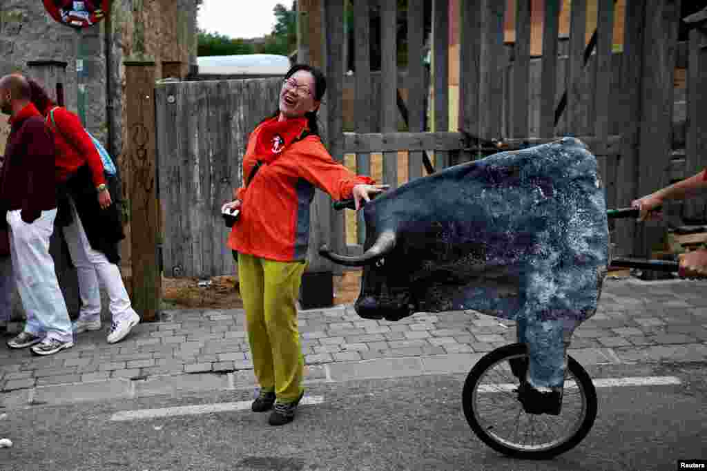 A woman is surprised by a toy bull during the Encierro Txiki (Little Bull Run) at the San Fermin festival in Pamplona, Spain.