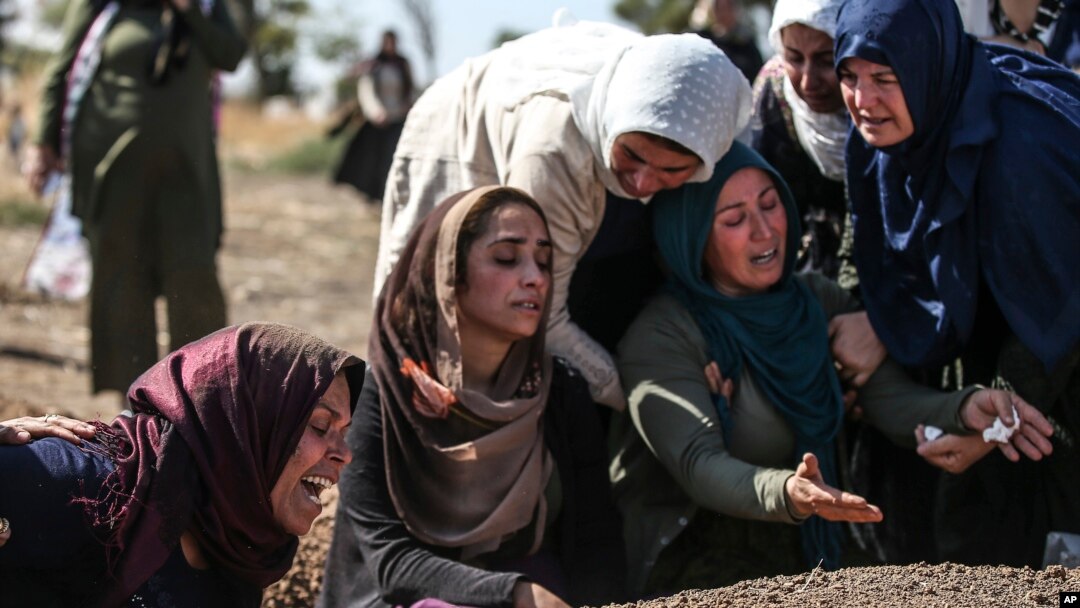 Relatives of Halil Yagmur, 64, who was killed Friday during mortar shelling from Syria, mourn over his grave at the cemetery in the town of Suruc, southeastern Turkey, at the border with Syria, Oct. 12, 2019. 