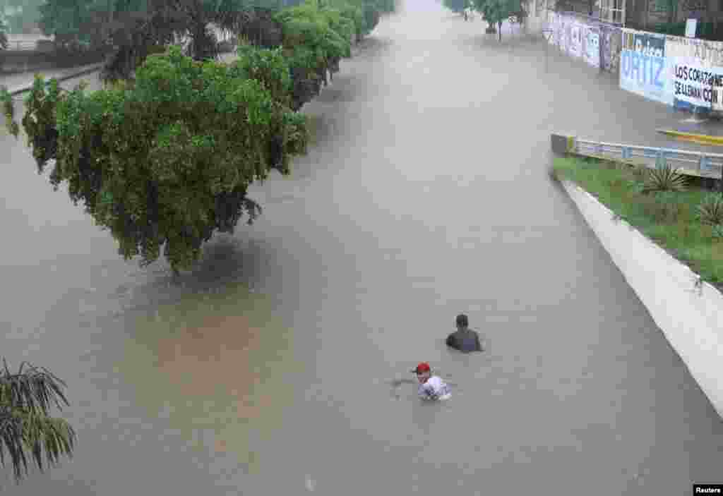 People swim in flood waters in Culiacan, Mexico, Sept. 19, 2013.