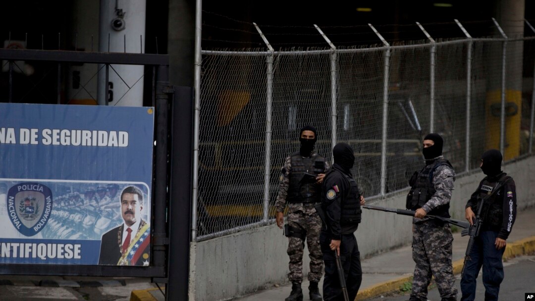 Un grupo de policías con el rostro cubierto hacen guardia en la puerta principal de la sede del SEBIN en Caracas, Venezuela, el 16 de mayo de 2018.