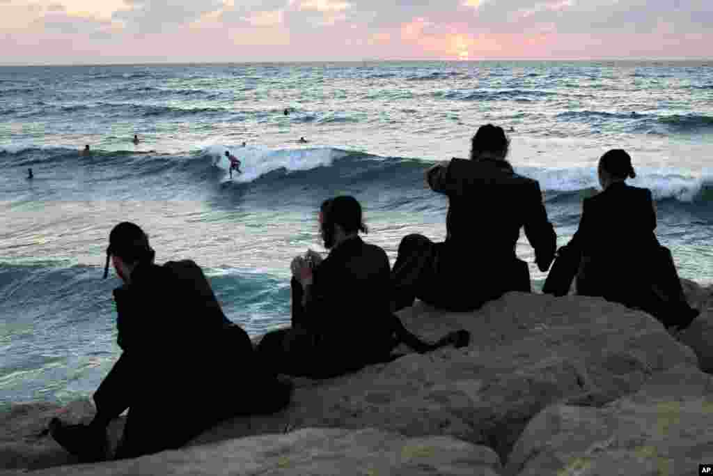 Ultra-Orthodox Jewish men watch Israeli surfers during the Jewish holiday of Sukkot in the southern Israeli port city of Ashdod, Sept. 23, 2013.