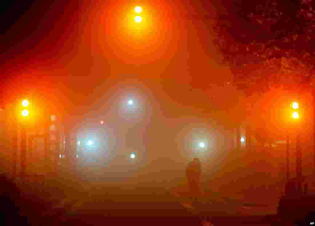 A woman crosses the street on a foggy morning in Frankfurt, Germany, Oct. 29, 2021.