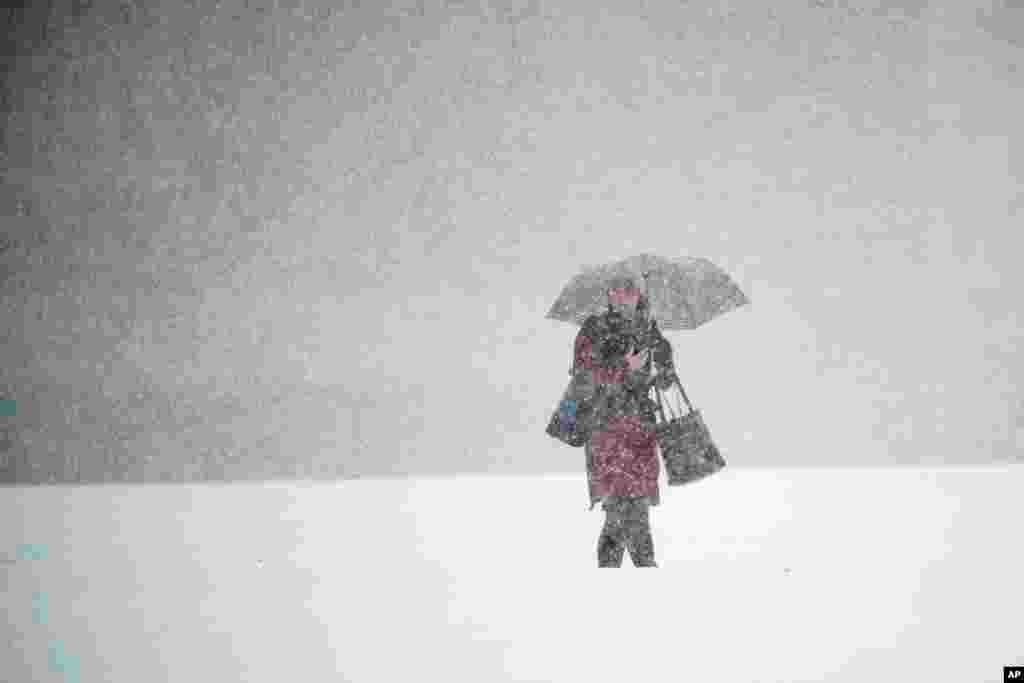 A person walks across Independence Mall during a snow storm in Philadelphia, Pennsylvania.