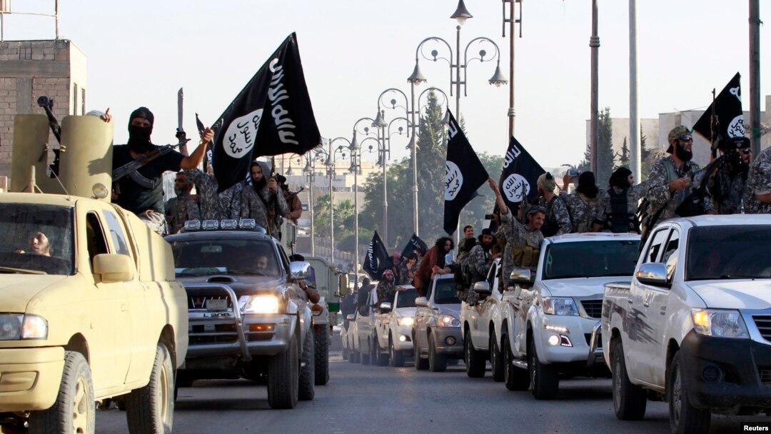 FILE - Islamic State fighters parade on military vehicles along the streets of Syria's northern Raqqa province.