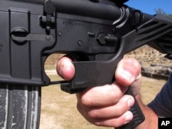 FILE - Shooting instructor Frankie McRae demonstrates the grip on an AR-15 rifle fitted with a bump stock at his 37 PSR Gun Club in Bunnlevel, N.C., Oct. 4, 2017.
