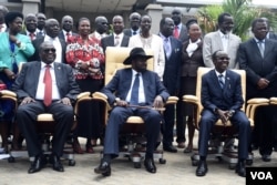 South Sudan's President Salva Kiir, center, laughs with First Vice President Riek Machar, left, and Vice President James Wani Igga, right, while cabinet members stand behind them, after the first meeting of a new transitional government of national unity,