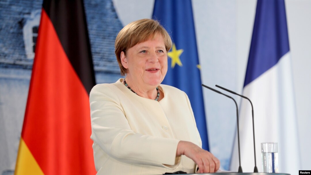 German Chancellor Angela Merkel, left and French President Emmanuel Macron talk in the garden of Meseberg Castle, the German government's guest house in Meseberg, Germany, June 29, 2020.