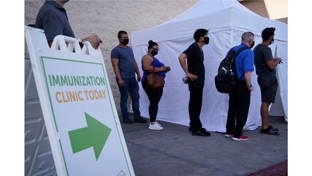 FILE- People wait in line for COVID-19 vaccinations at an event at La Bonita market, a Hispanic grocery store, in Las Vegas, July 7, 2021.