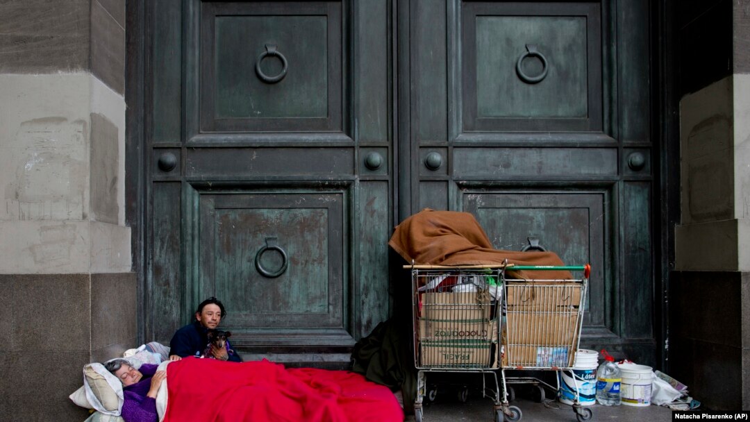 Maria Susana Silveira, 55, and Jorge Fernandez, 46, who live in the street as a team, rest outside Banco Nacion with their dog Toto, across the street from La Casa Rosada presidential house in Buenos Aires, Argentina.