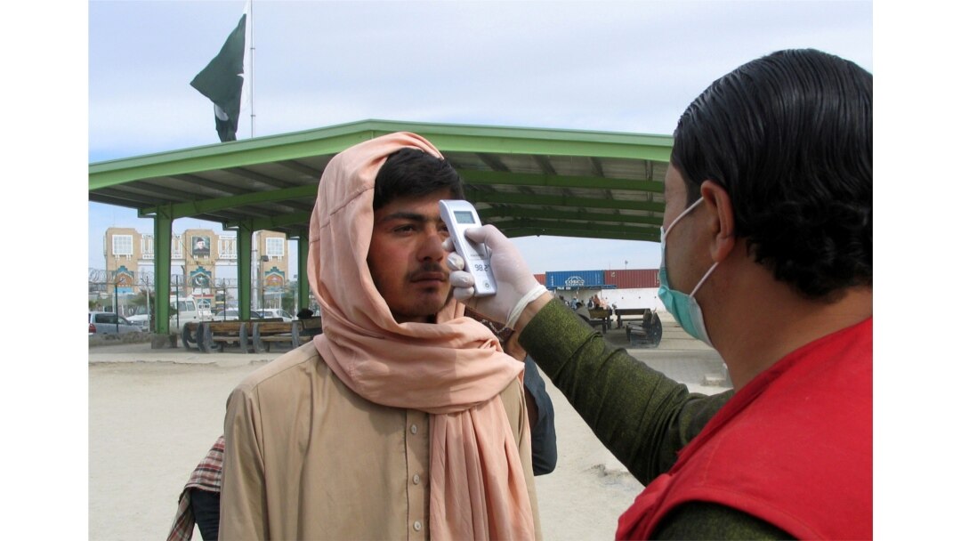 FILE - A health worker takes the temperature of a Afghan national at the Chaman crossing point on the Pakistan-Afghanistan border, in Chaman, Pakistan, Feb. 26, 2020.