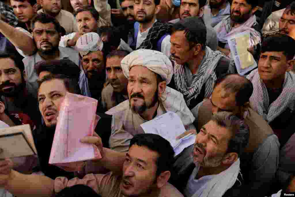 Afghans gather outside the passport office after Taliban officials announced they will start issuing passports to its citizens again, following months of delays that hampered attempts by those trying to flee the country after the Taliban seized control, in Kabul, Afghanistan.