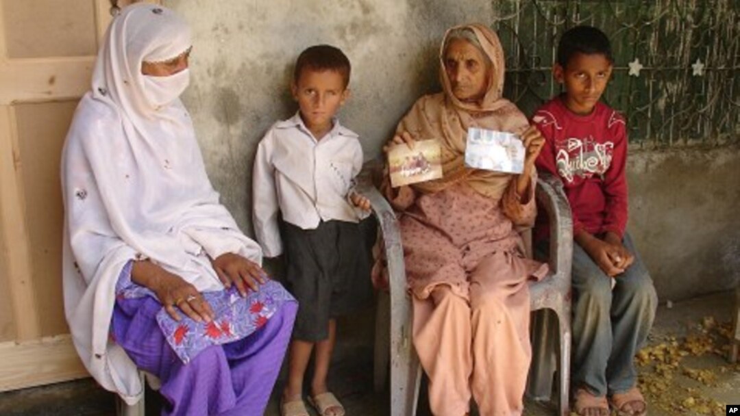 Pakistan's Noor Bibi, second from right, shows pictures of her husband and son whom she alleges were picked up by security agencies last week as she sits with unidentified family members in Abbottabad, Pakistan, June 15, 2011