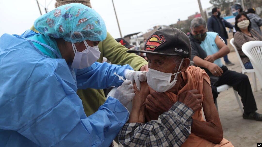 Eighty five-year-old Crisologo Enriquez holds steady as he receives a influenza vaccine during a vaccination campaign and COVID-19 testing operation in the Villa El Salvador neighborhood of Lima, Peru, June 26, 2020.