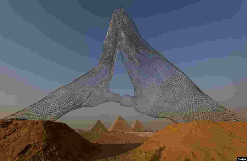 A view of the sculpture 'Together' by Italian sculptor Lorenzo Quinn, son of late actor Anthony Quinn, is seen in front of the Great Pyramids of Giza, on the outskirt of Cairo, Egypt, Oct. 23, 2021.