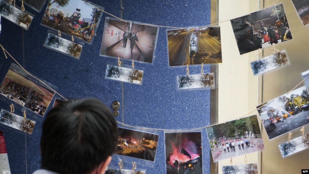 FILE - This photograph taken on Nov. 14, 2020 shows a photographer in front of pictures depicting the 2019 campus siege at the height of the city's pro-democracy protests at an exhibition in the Chinese University of Hong Kong.