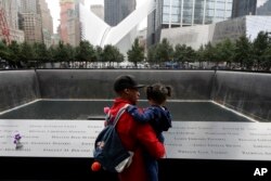Un hombre y su hija observan la fuente norte en el World Trade Center en Nueva York durante la ceremonia recordatorai de los ataques terroristas de 2001 el martes, 11 de septiembre de 2018.