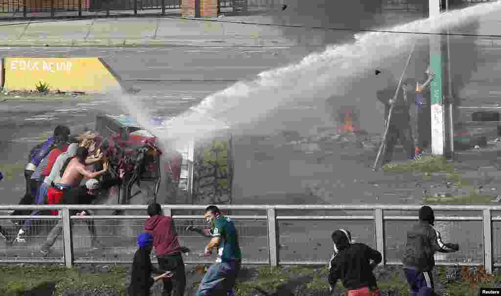 Fishermen push a part of a burnt truck against a water cannon as they clash with riot policemen during a protest against a fisheries law, which they say the government has failed to improve, in Valparaiso city, northwest of Santiago, Chile, July 2, 2014.
