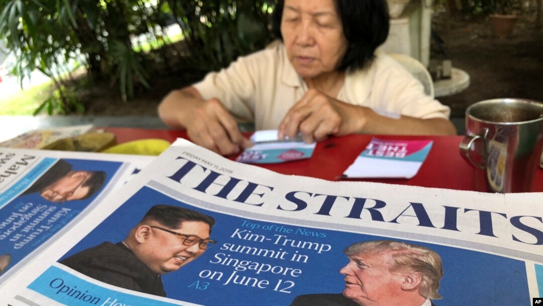 A news vendor counts her money near a stack of newspapers with a photo of U.S. President Donald Trump, right, and North Korea's leader Kim Jong Un on its front page in Singapore, May 11, 2018. 