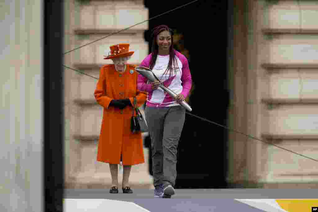 Baton bearer Kadeena Cox of Britain, who won two gold medals at the Rio 2016 Paralympic Games, receives from Queen Elizabeth II the baton to be used at the Birmingham 2022 Commonwealth Games Queen's Baton Relay event, outside Buckingham Palace in London.