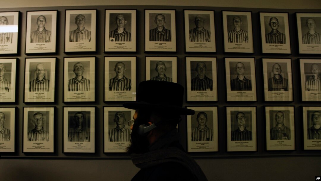 Un judío ortodoxo pasa frente a los retratos de las víctimas en el antiguo campo de concentración y exterminio nazi alemán Auschwitz-Birkenau en Oswiecim, Polonia, el jueves 26 de enero de 2023.