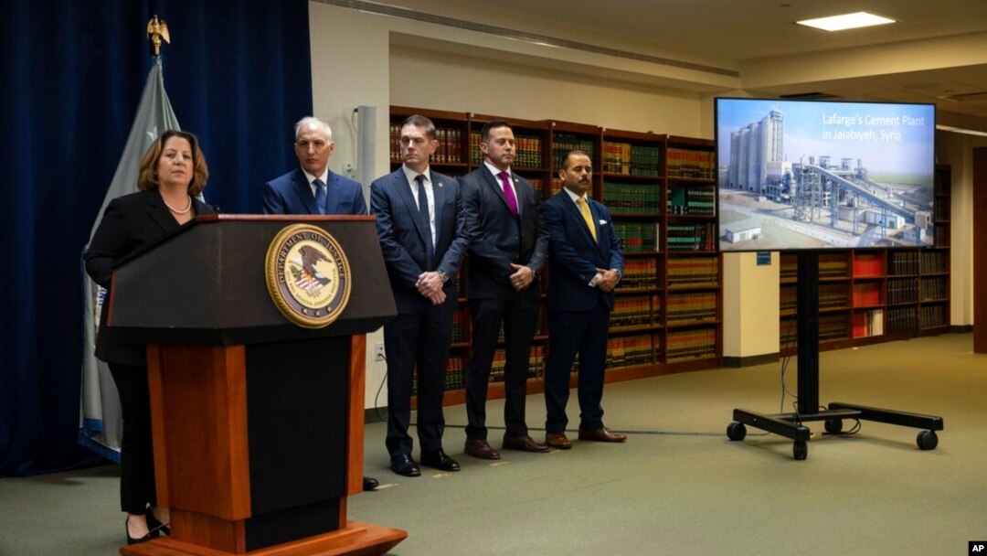 A screen shows a photo of Lafarge's cement plant in Jalabiyeh, Syria, as the deputy Attorney General of the United States Lisa Monaco, left, speaks during a press conference at the U.S. Attorney's Office in New York, Oct. 18, 2022.
