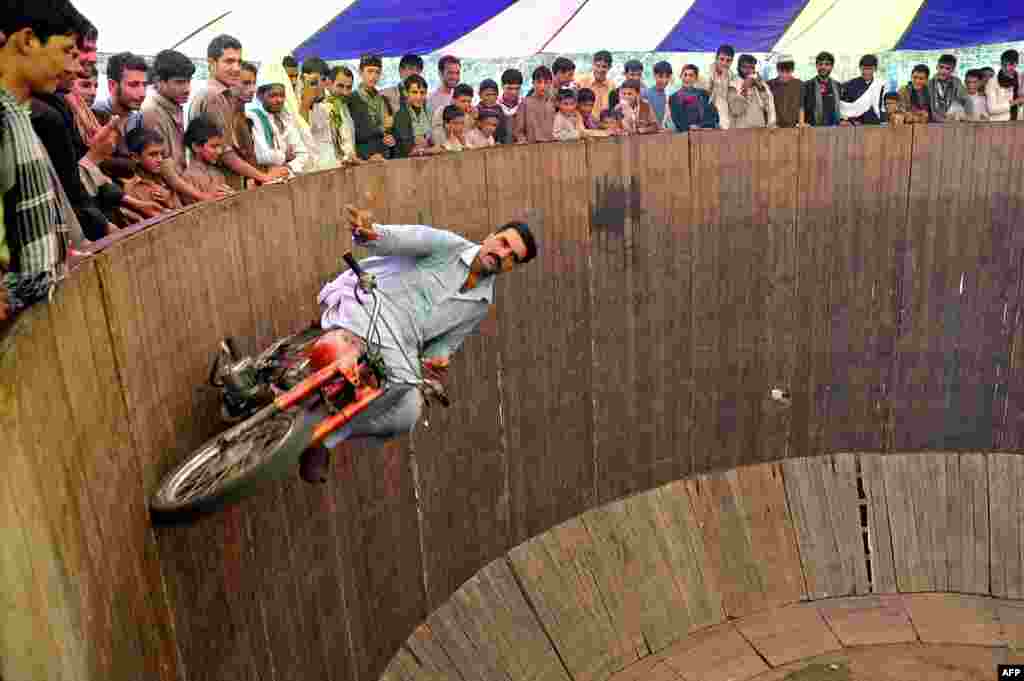 An Afghan circus performer rides a motorcycle on the " Wall of Death" at a fair on the second day of Eid al-Fitr in Jalalabad, Afghanistan.