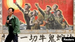一名男子走過寧夏銀川街頭郊區的一處描寫中國文革的宣傳畫。（2007年4月25日）