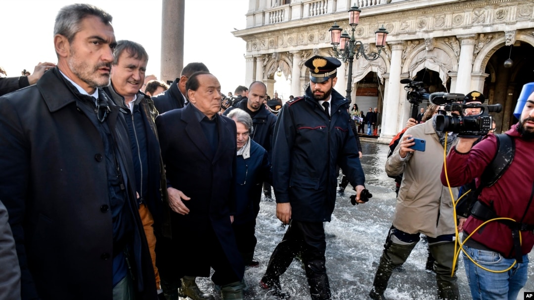 El ex primer ministro italiano Silvio Berlusconi, 3ro desde la izquierda, acompañado del alcalde de Venecia Luigi Brugnaro, izquierda, y otros funcionarios caminan en medio del agua en la Plaza de San Marcos en Venecia. nov.14, 2019. AP/Luigi Constantini.