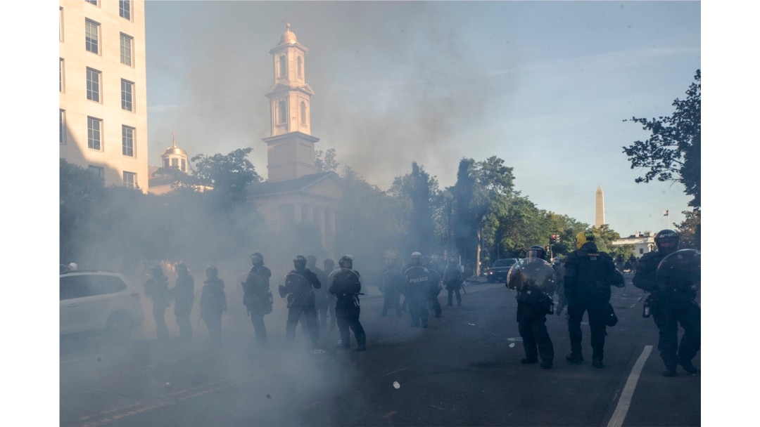 FILE - Tear gas floats in the air as a line of police move demonstrators away from St. John's Church across Lafayette Park from the White House, as they gather to protest the death of George Floyd, June 1, 2020, in Washington.