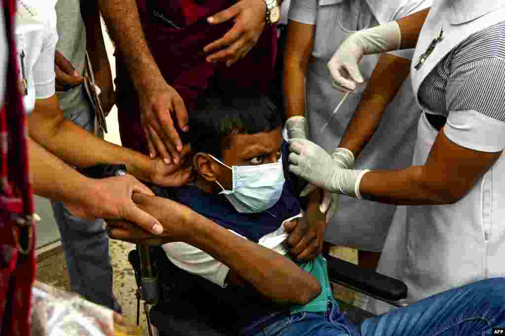 A health worker inoculates a child with a dose of the Pfizer-BioNTech vaccine against COVID-19 at a children's hospital in Colombo, as Sri Lanka began inoculating children over 12.