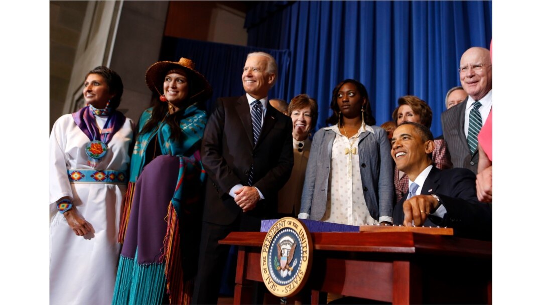 President Barack Obama signs the Violence Against Women Reauthorization Act of 2013 while Vice President Joe Biden looks on, in Washington, March 7, 2013.
