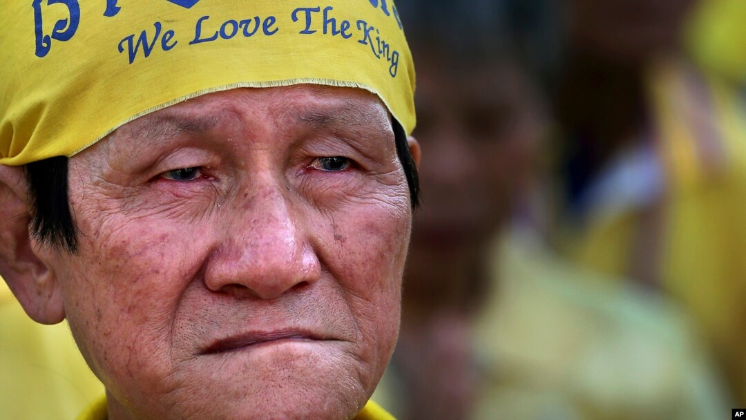 FILE - An elderly man listens to King Bhumibol Adulyadej make a speech on a giant screen, on the king's 86th birthday at the Democracy Monument in Bangkok, Dec. 5, 2013.