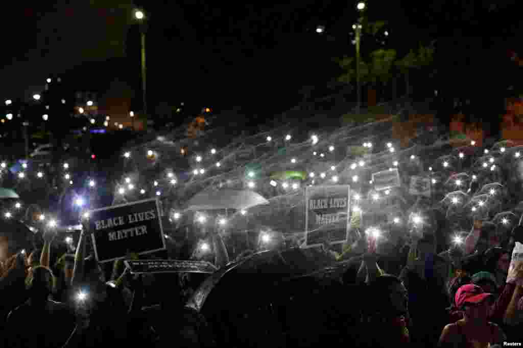 Demonstrators hold up their mobile phones as they continue to protest for a fourth day after the not guilty verdict in the murder trial of Jason Stockley, a former St. Louis police officer, charged with the 2011 shooting of Anthony Lamar Smith, who was black, in St. Louis, Missouri, Sept. 18, 2017.